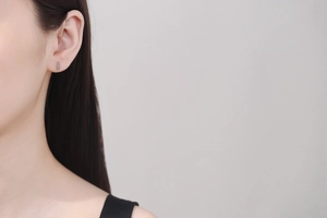 Close-up of three-stone moissanite stud earrings in rose gold on a model ear