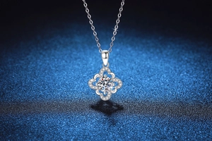 Macro shot of silver four-leaf clover necklace with 1-carat moissanite on blue background