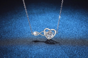 Macro shot of silver heart and infinity pendant with bright round cut moissanite