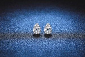 Detail view of pear-shaped halo earrings with round moissanite in polished silver