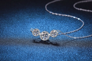 Détail du collier en argent S925 avec trois pierres moissanite rondes sur fond bleu