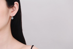 Close-up of S925 silver round moissanite drop earrings worn by a model in soft light