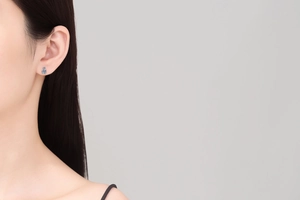 Detailed view of a woman wearing a minimalist S925 silver stud earring with a blue moissanite