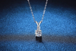 Macro shot of 925 silver necklace with four-prong moissanite pendant on blue background