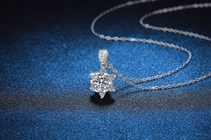 Macro view of snowflake moissanite pendant with fine silver chain on dark blue base