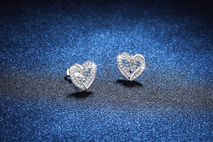 Detail of S925 sterling silver heart-shaped moissanite earrings on blue background