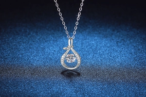 Macro shot of dancing moissanite stone inside a silver water-drop pendant necklace
