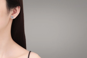 Detail of S925 silver heart earring with blue moissanite on model ear with high clarity