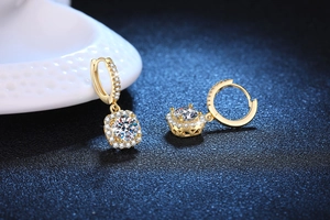 Macro detail of gold moissanite hoop earrings with a square halo and brilliant clear stones