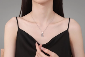 Detail of S925 silver moon and star pendant necklace on model with black silk dress