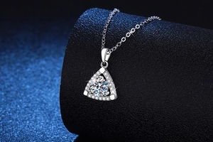 Macro di un ciondolo a triangolo in argento con moissanite tonda su catena a croce