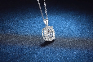 Macro shot of S925 sterling silver halo pendant with 1ct moissanite on a blue surface