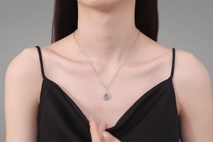 Macro detail of teardrop moissanite pendant with blue center stone and silver chain