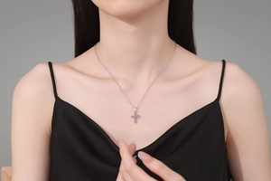 Close-up of S925 sterling silver cross necklace with light blue moissanite on model