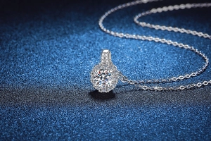 Vue macro d'un pendentif halo en moissanite 1 carat sur chaîne argent et fond bleu étoilé