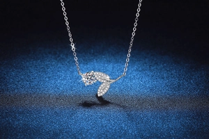 Close-up of 925 sterling silver leaf pendant with 1ct moissanite on starry background