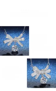 Macro detail of Moissanite bow necklace pendant in polished silver setting with pave stones