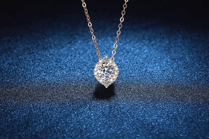 Makroaufnahme einer roségoldenen Kette mit Moissanit-Halo-Anhänger auf blauem Stoff