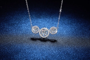Macro close-up of three-stone moissanite pendant on S925 silver chain over dark blue background