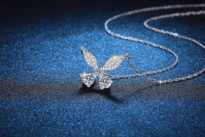 Macro shot of a 925 sterling silver butterfly pendant with moissanite stones on blue texture