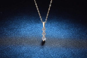 Macro detail of three-stone moissanite pendant on a gold chain with star background