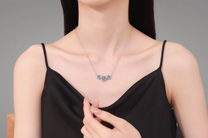 Three-stone moissanite pendant necklace on a model with elegant black silk dress