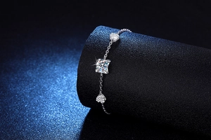 Close-up of s925 silver bracelet featuring heart charms and a radiant square-cut stone
