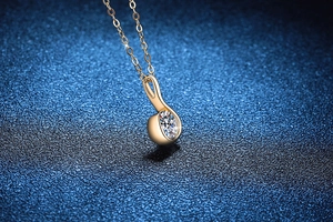 Macro shot of 1 carat moissanite pendant on a gold chain over deep blue background