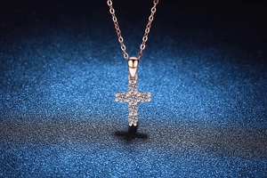 Close-up of a 925 silver cross pendant with rose gold plating and round cut moissanite