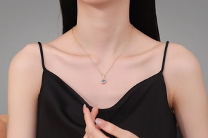 Detail view of a 1 carat blue moissanite musical note pendant on a gold necklace
