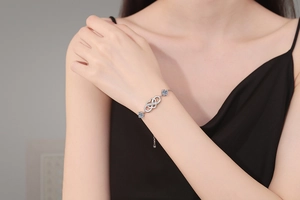 Detail view of S925 silver infinity heart bracelet with blue moissanite on a female wrist