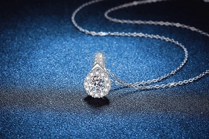 Vista macro di una collana di moissanite in argento 925 con ciondolo a corona su fondo blu
