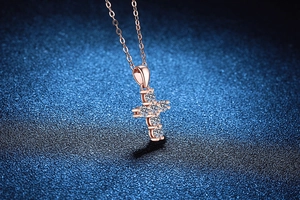 Macro shot of rose gold cross pendant featuring six sparkling moissanite stones on a fine chain
