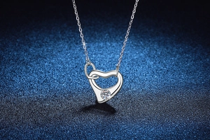 Macro view of S925 silver heart necklace with moissanite on dark blue background