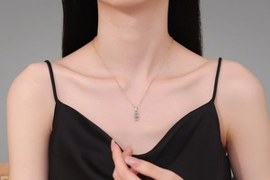 Detail of model wearing a gold necklace with three vertically set blue moissanite stones