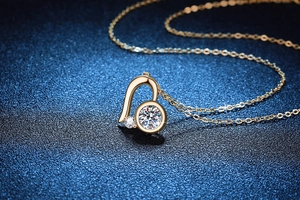 Macro d'un collier cœur asymétrique en or orné d'une pierre de moissanite taille brillant