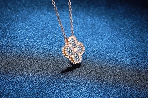 Macro view of rose gold four-leaf clover pendant with 1.2ct Moissanite diamond