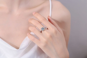 Nahaufnahme eines Halo-Rings mit Moissanit-Rundschliff in Silberfassung auf einem Finger