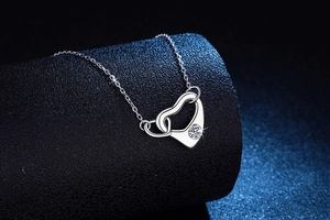 Macro detail of S925 silver interlocking heart necklace with a sparkling round moissanite