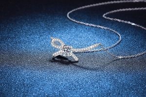 Dettaglio macro del ciondolo a fiocco in argento 925 con moissanite su sfondo blu