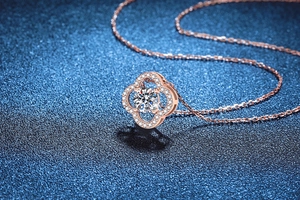 Detail view of rose gold four-leaf clover pendant with sparkling moissanite stone