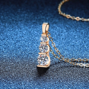 Three-stone graduated Moissanite pendant necklace in rose gold on deep blue background