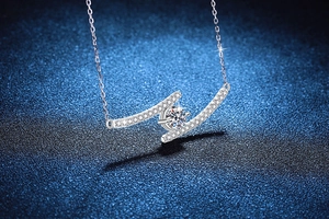 Macro view of 1 carat moissanite pendant with curved silver lines on dark background
