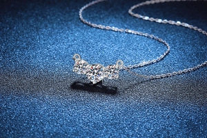 Macro shot of three moissanite diamonds set in a curved sterling silver pendant necklace