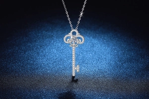 Macro shot of silver S925 key pendant necklace with moissanite stones on blue background