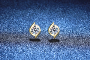 Macro shot of gold S925 sterling silver studs with 1 carat moissanite and swirl frame