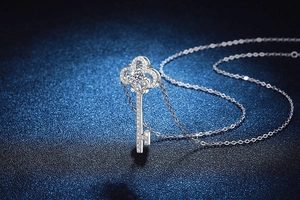 Macro shot of silver key pendant necklace with intricate hollow design and zircon pavé