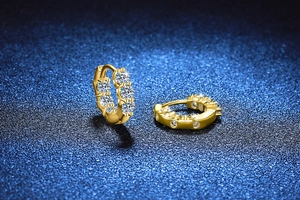 Detailed top view of gold hoop earrings with pavé set moissanite stones on blue background