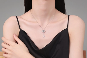 Detail of S925 silver key pendant necklace with blue gemstone and pavé stones on a model