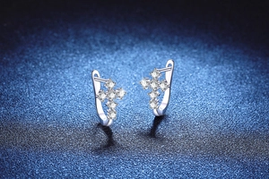 Gros plan de boucles d'oreilles croix en argent 925 avec moissanite sur fond bleu